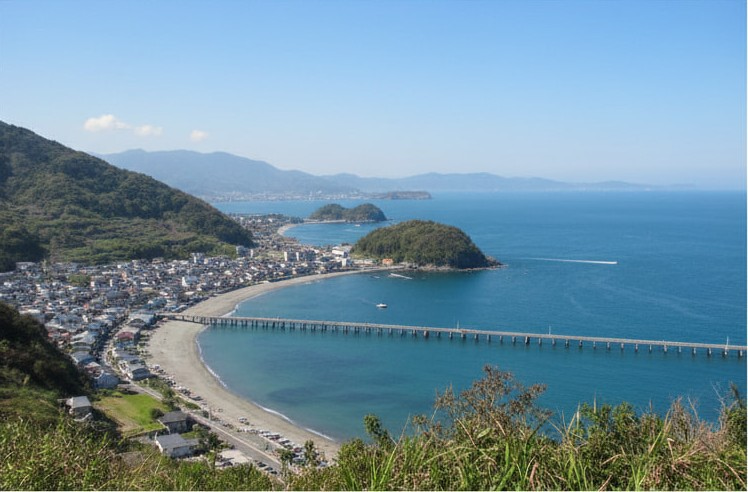 海沿いの高台にある休憩スポットから、眼下に広がる海と湾、そして小さな街並みを眺めるバイクのイラスト。広い駐車場には数台のバイクが停まっており、ライダーが景色を楽しんでいる。