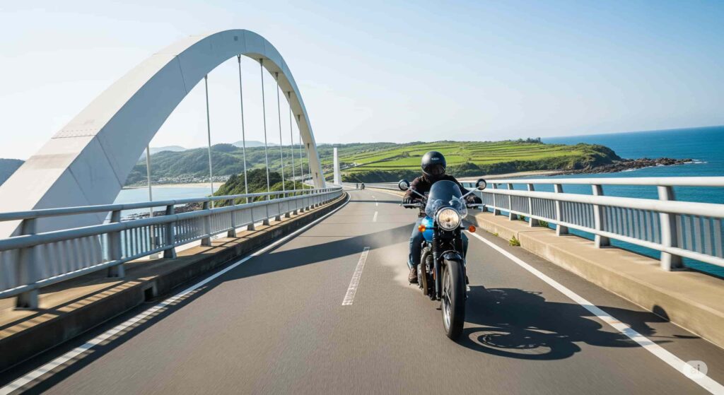 佐賀県の呼子大橋を渡るバイク。橋の向こうには加部島の緑の牧草地と青い海が広がっている。